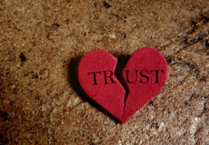 A broken heart with the word "TRUST" on the two pieces after an affair or broken promises in a marriage. Couples therapy in Fairfax, VA can help rebuild trust after infidelity. Marriage counseling in Fairfax, VA can help you heal after an affair at The Center for Connection, Healing and Change. 22032
